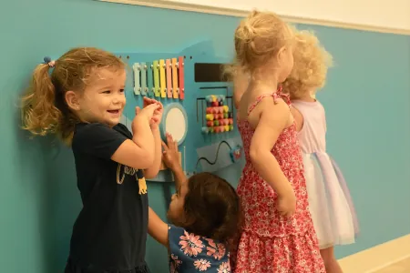 Toddlers playing with an activity wall panel