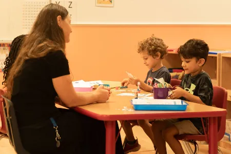 Teacher helping children with an activity at a table