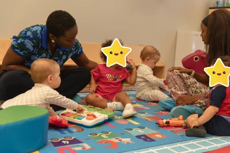 Teachers playing with infants and toddlers on a play mat
