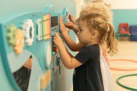 Toddler playing with an activity wall panel