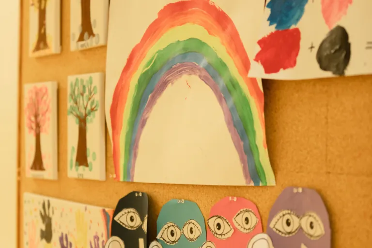 Children's rainbow and tree artwork on the classroom wall