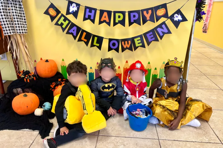 Children in costumes under a Happy Halloween banner