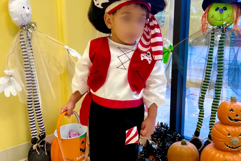 Child in a pirate costume beside Halloween decorations