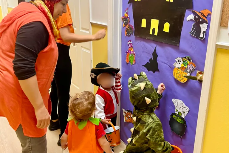 Children in costumes walking past decorated classroom doors