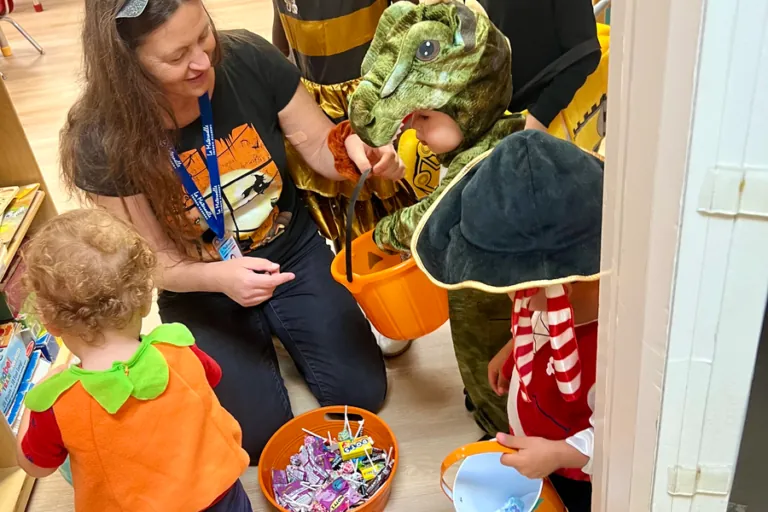 Teacher handing out candy to children in costumes