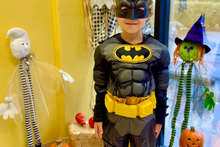 Child in a Batman costume next to Halloween decorations
