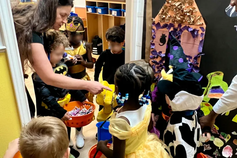 Teachers handing candy to children in costumes