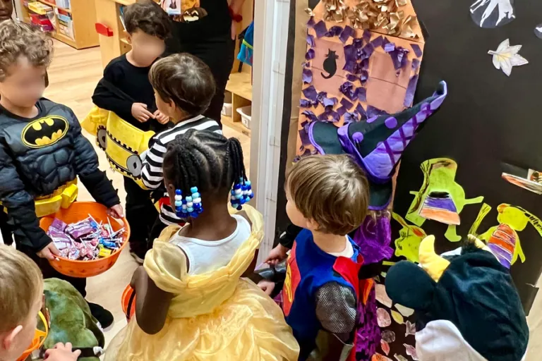 Children with candy bags in front of a decorated classroom door