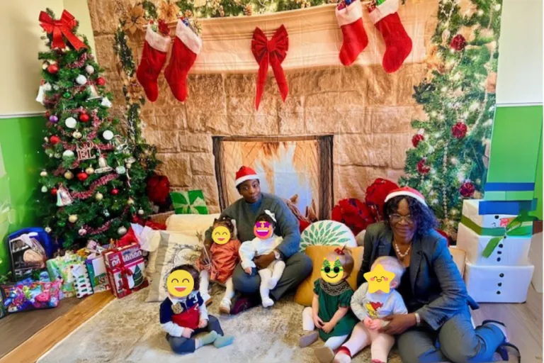 Teachers and children by the fireplace and Christmas tree