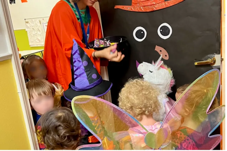 Teacher in costume greeting children trick-or-treating