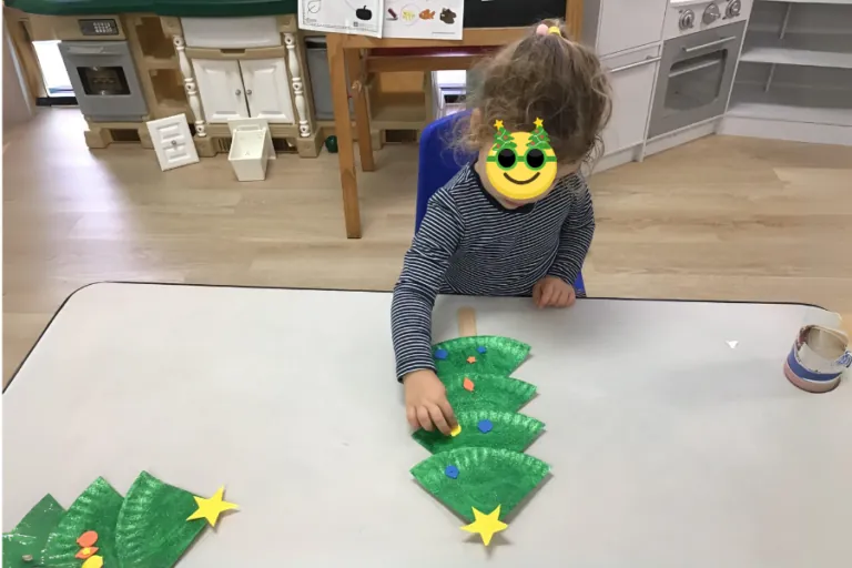 Child building with green blocks at a classroom table