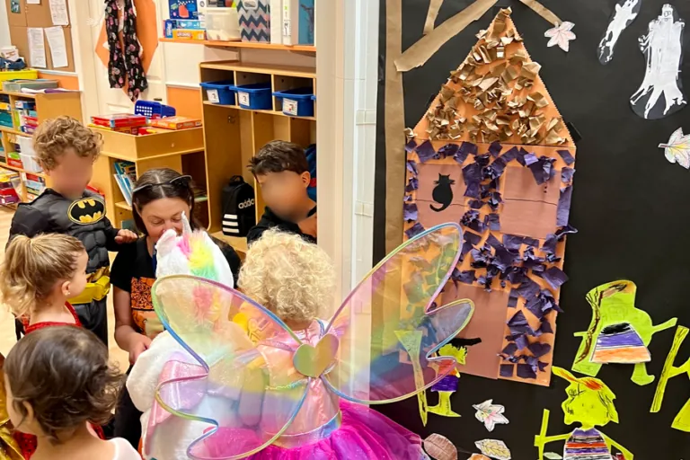 Children in costumes by a decorated Halloween door