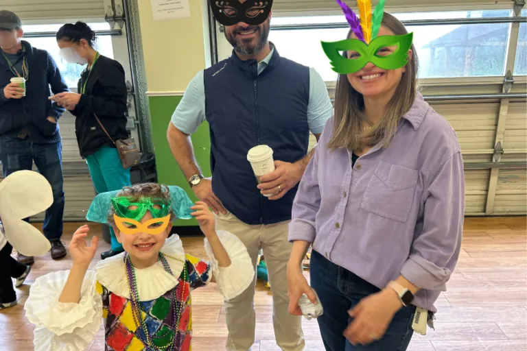 Parents and children in Mardi Gras masks at the Carnival celebration