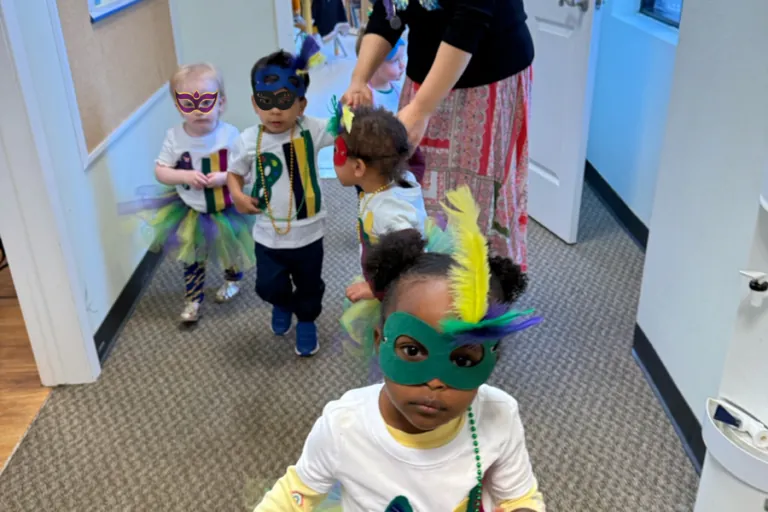 Children in masks walking down the school hallway during Carnival