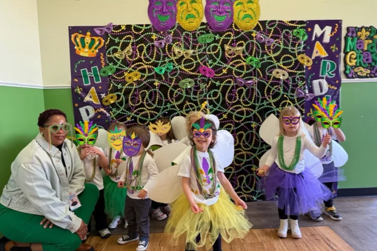 Children in costume posing in front of the Mardi Gras photo wall